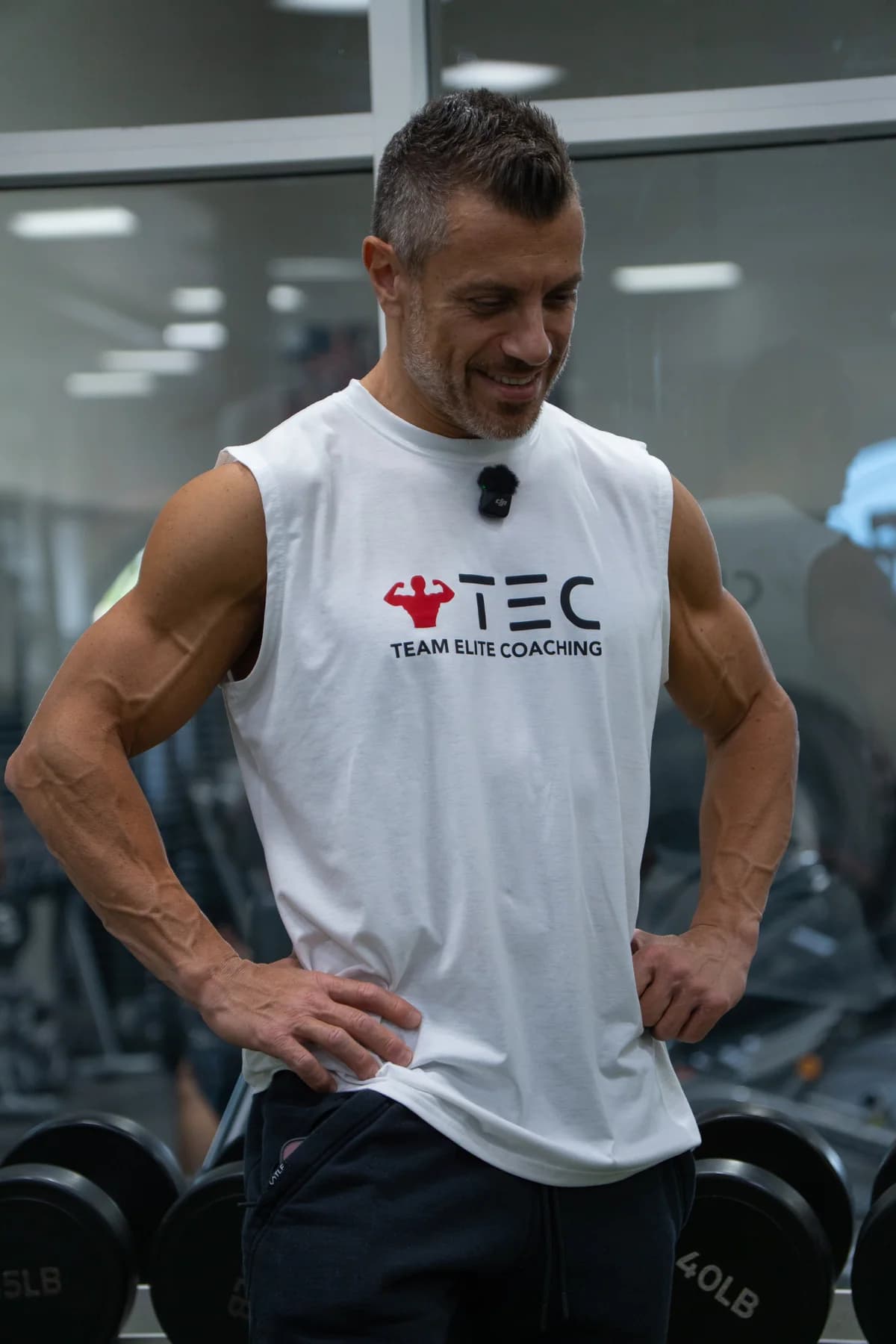 Solo gym portrait in a white Team Elite Coaching shirt.